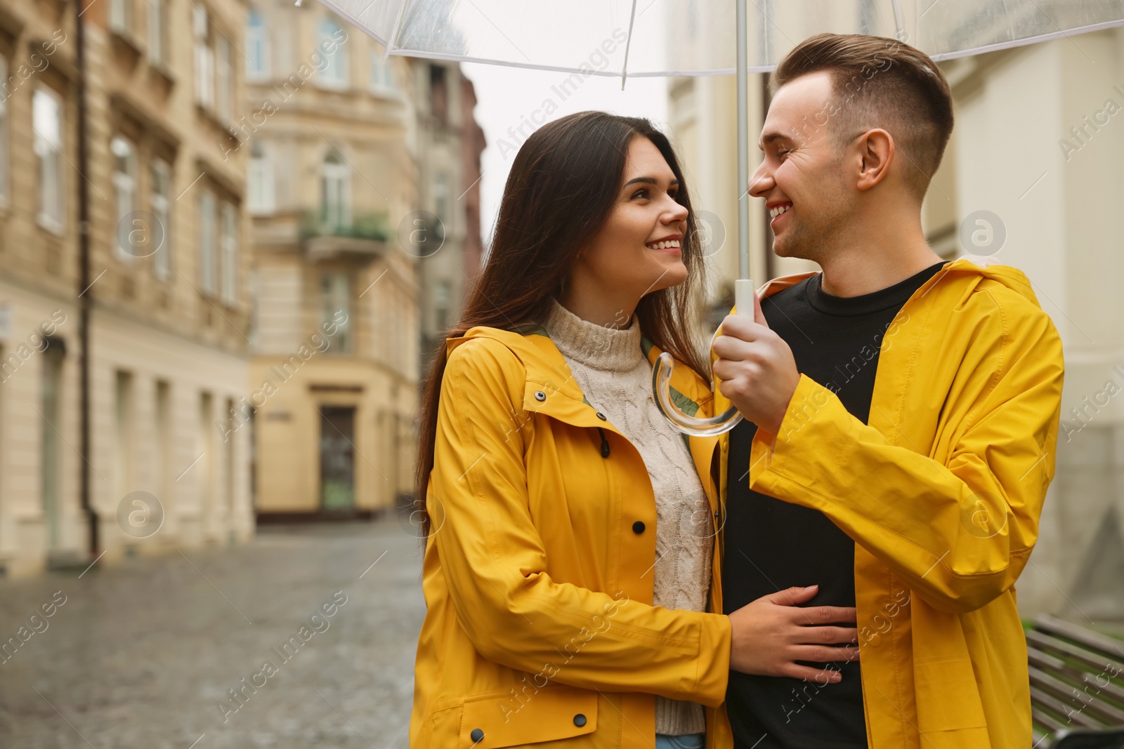 Photo of Lovely young couple with umbrella walking under rain on city street