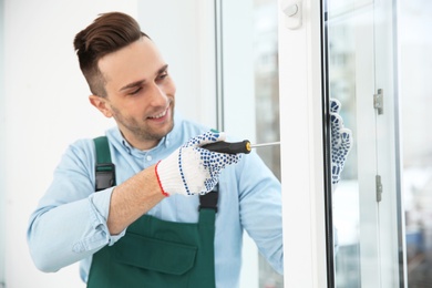 Construction worker adjusting installed window with screwdriver indoors