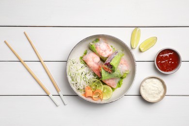 Photo of Delicious spring rolls wrapped in rice paper served on white wooden table, flat lay