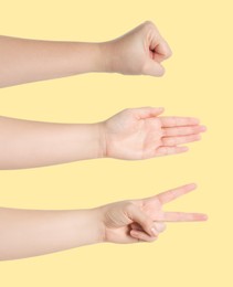 People playing rock, paper and scissors on yellow background, closeup