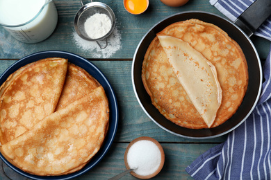 Photo of Flat lay composition with thin pancakes on blue wooden table