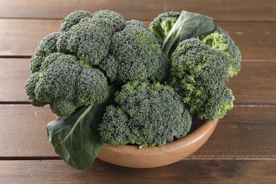 Photo of Bowl with fresh raw broccoli on wooden table, closeup