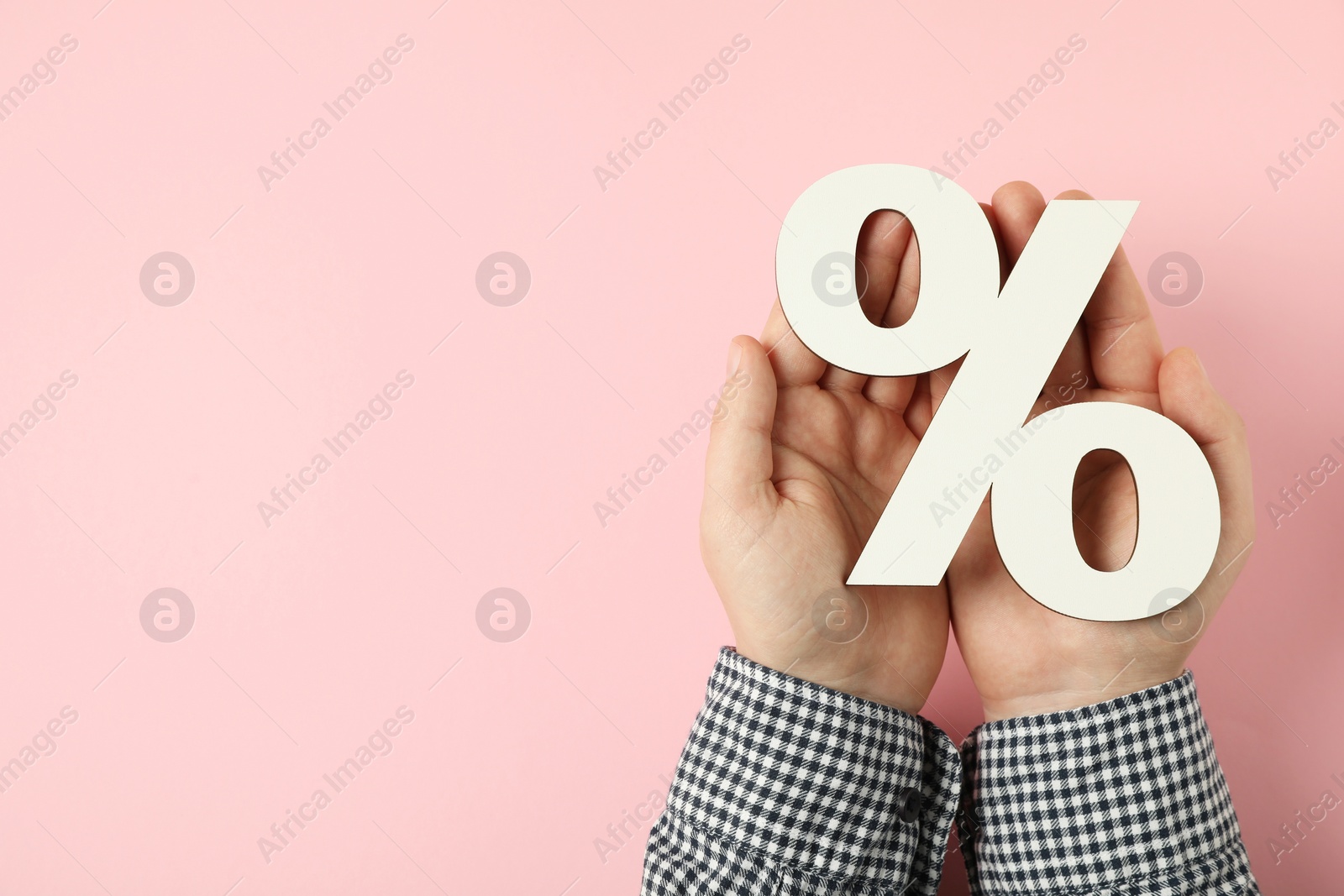 Photo of Man holding percent sign on pink background, top view. Space for text