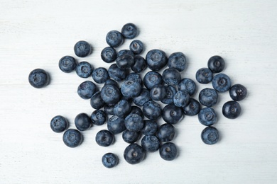 Photo of Pile of tasty fresh blueberries on white wooden table, top view
