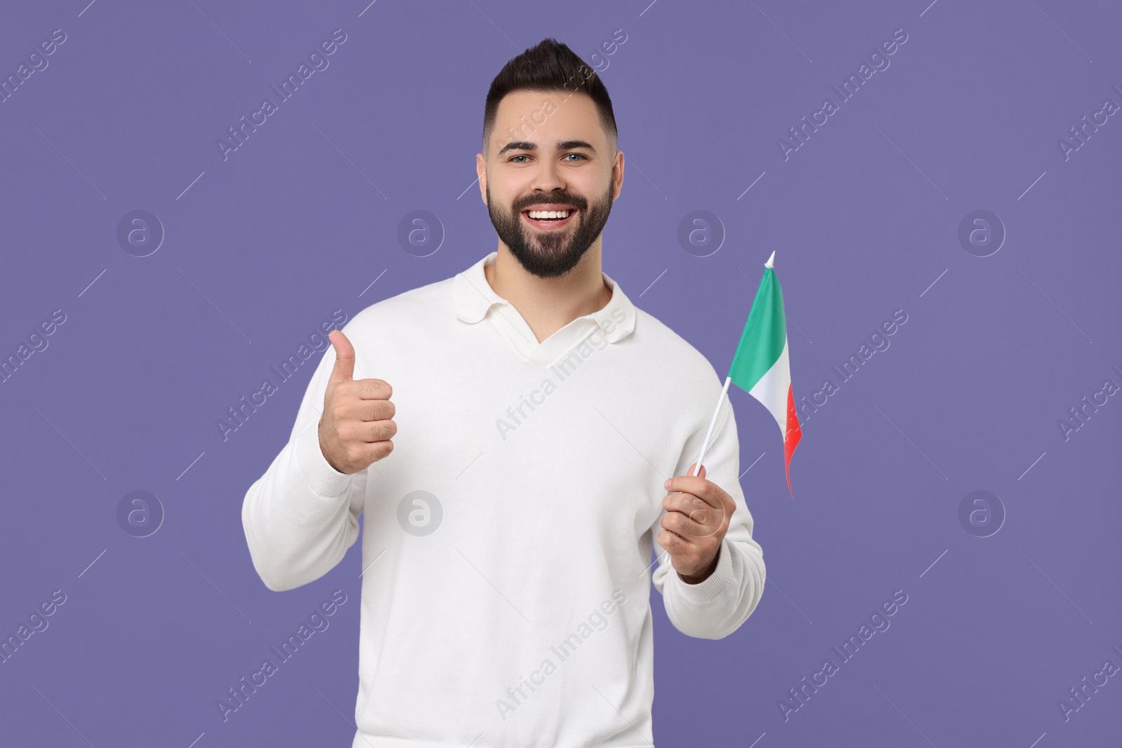 Photo of Young man with flag of Italy showing thumb up on purple background