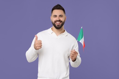 Photo of Young man with flag of Italy showing thumb up on purple background