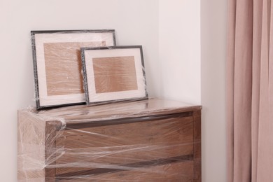 Photo of Picture frames and chest of drawers wrapped in stretch film indoors