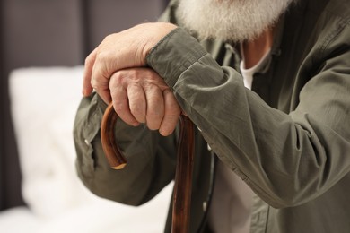 Photo of Senior man with walking cane indoors, closeup