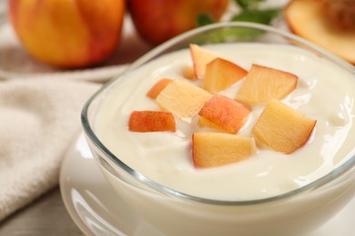 Photo of Delicious yogurt with fresh peach in glass bowl on table, closeup