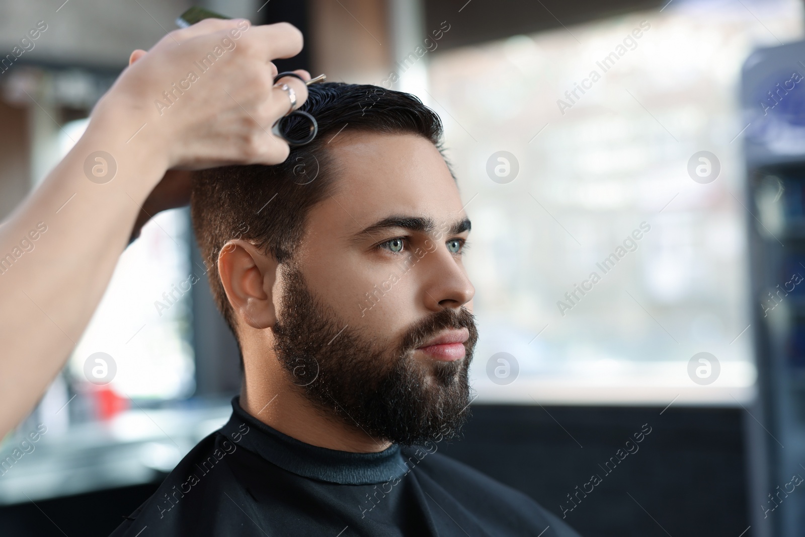 Photo of Professional hairdresser working with client in barbershop