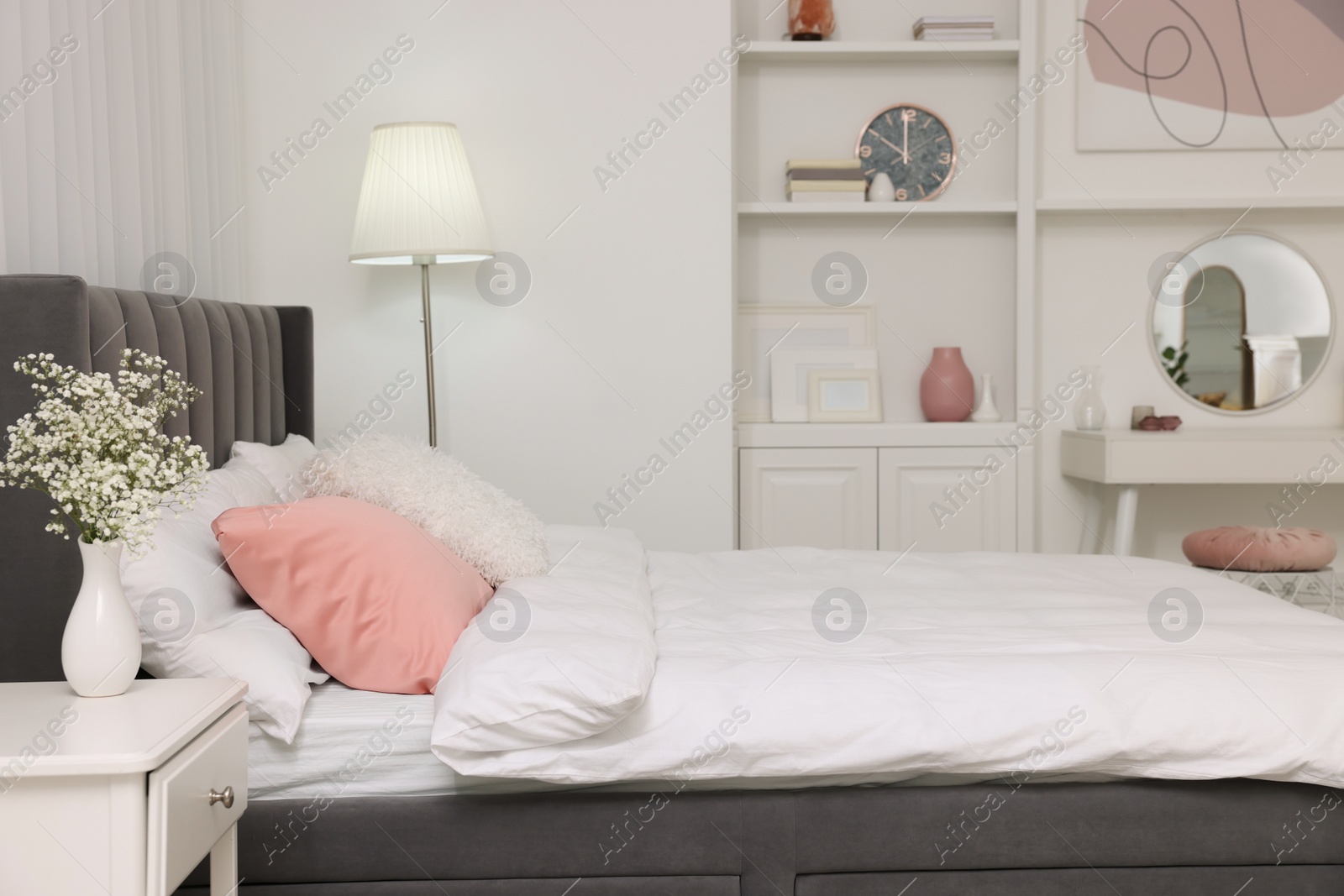 Photo of Stylish bedroom interior with comfortable bed, nightstand and lamp