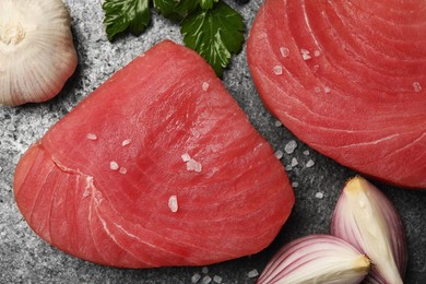 Raw tuna fillets with salt, parsley and shallot on gray table, flat lay