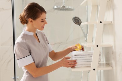 Chambermaid putting fresh flower on towels in hotel bathroom