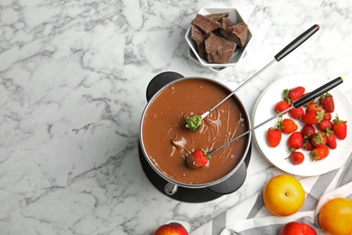 Photo of Flat lay composition with chocolate fondue in pot and space for text on marble background