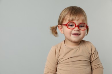 Photo of Cute little girl in glasses on light grey background. Space for text