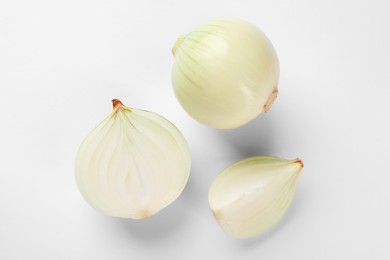 Photo of Whole and cut onions on white background, top view