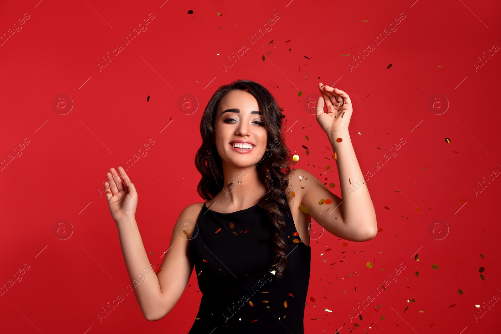 Photo of Beautiful young woman wearing elegant dress and confetti on red background. Christmas party