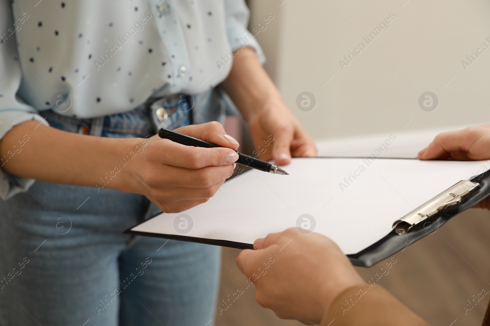 Photo of Woman signing rental agreement in clothing salon, closeup