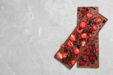 Chocolate bars with freeze dried berries on grey marble table, top view. Space for text