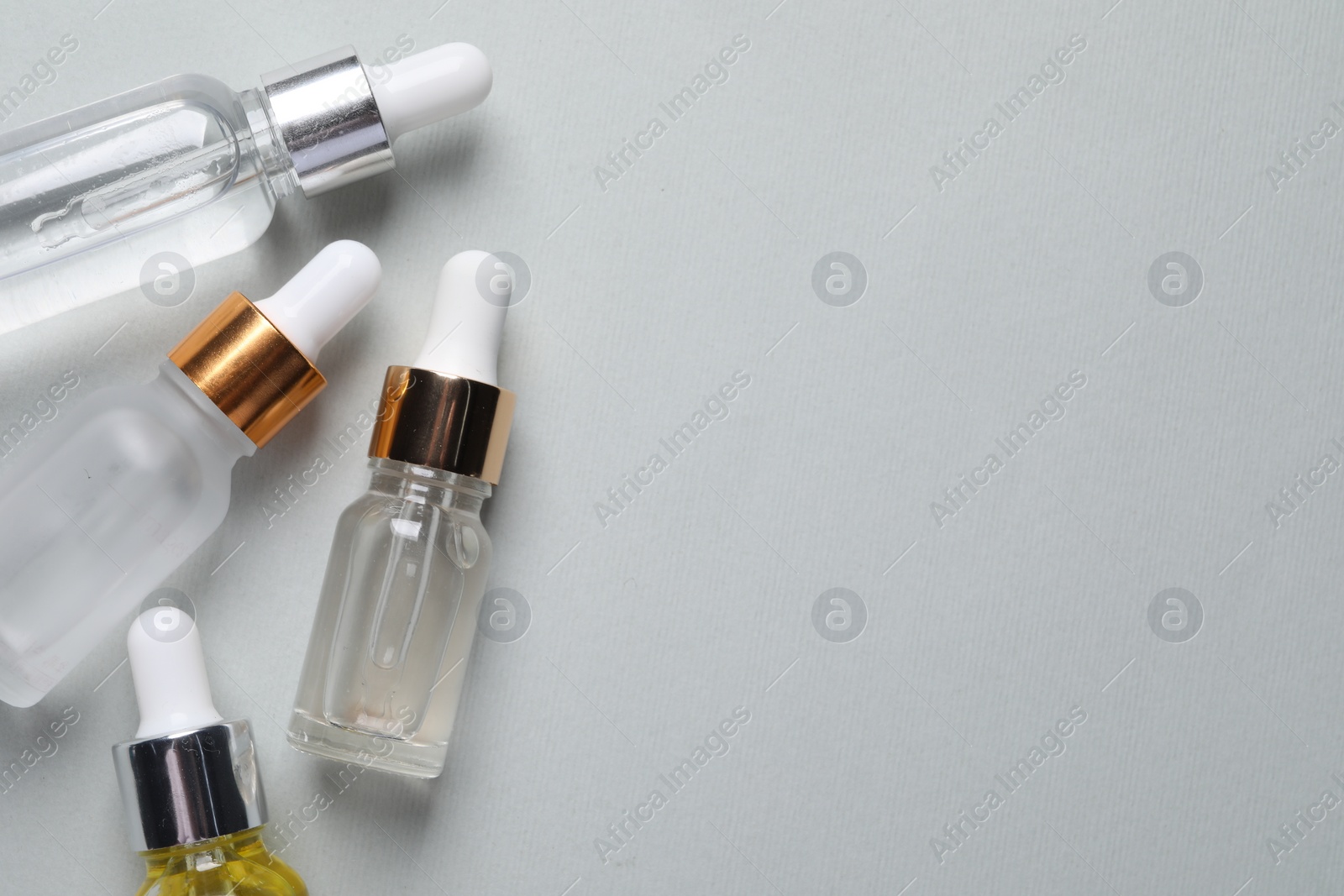 Photo of Many bottles of cosmetic serum on light grey background, flat lay. Space for text