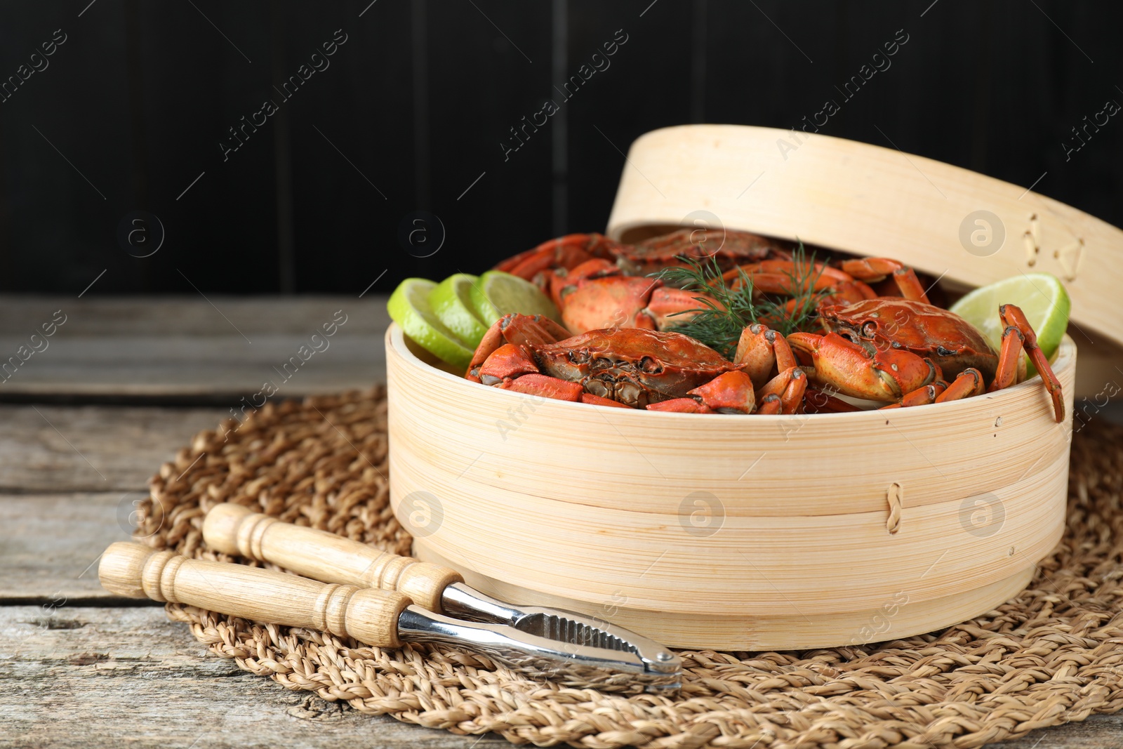 Photo of Delicious boiled crabs with lime and dill served on wooden table