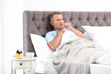 Man suffering from cough and cold in bed at home