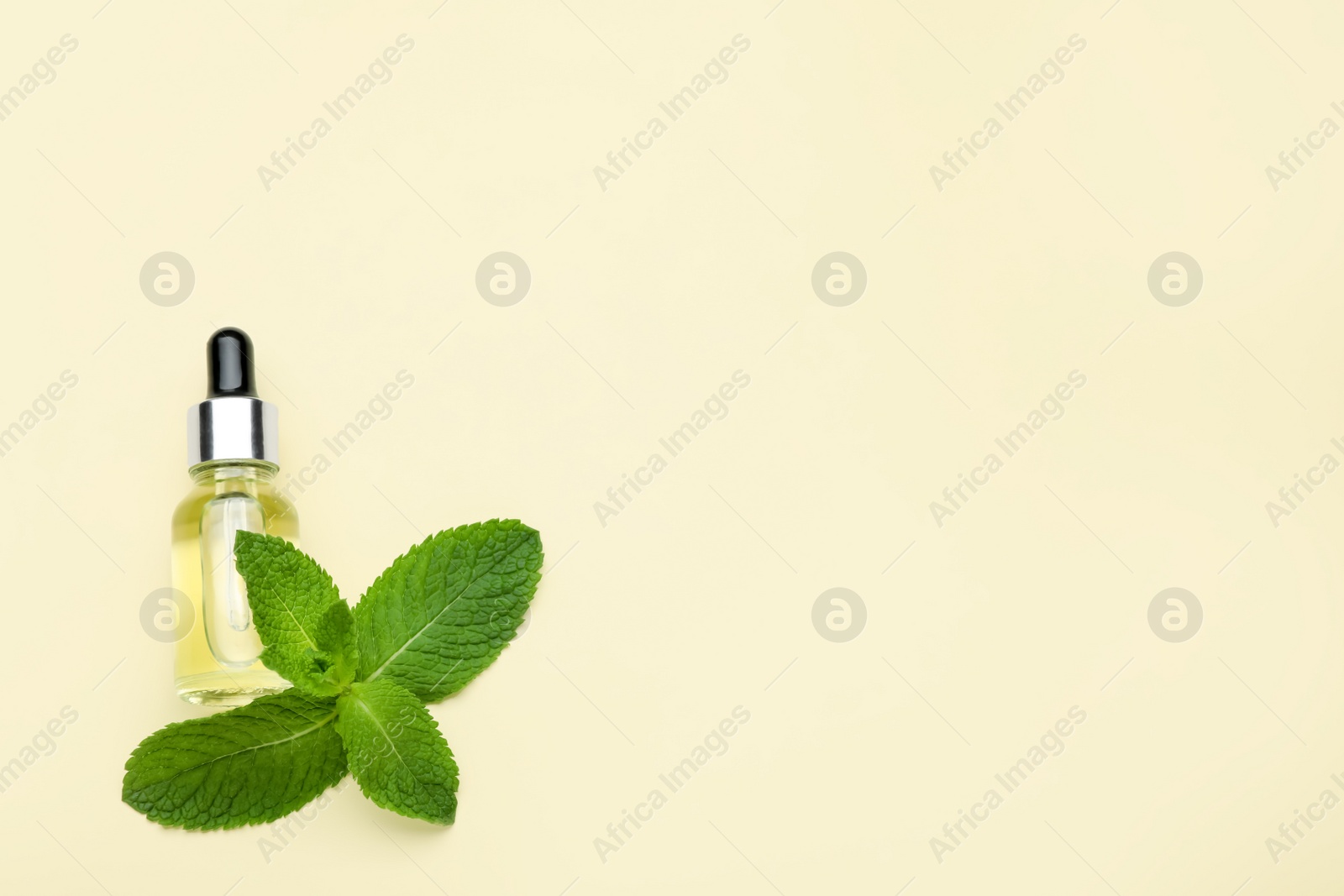 Photo of Bottle of essential oil and mint on beige background, flat lay. Space for text