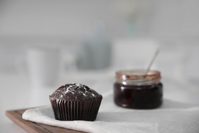 Photo of Delicious chocolate muffin on white table in kitchen. Space for text