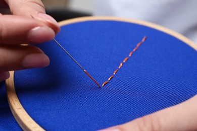 Woman with sewing needle and thread embroidering on cloth, closeup