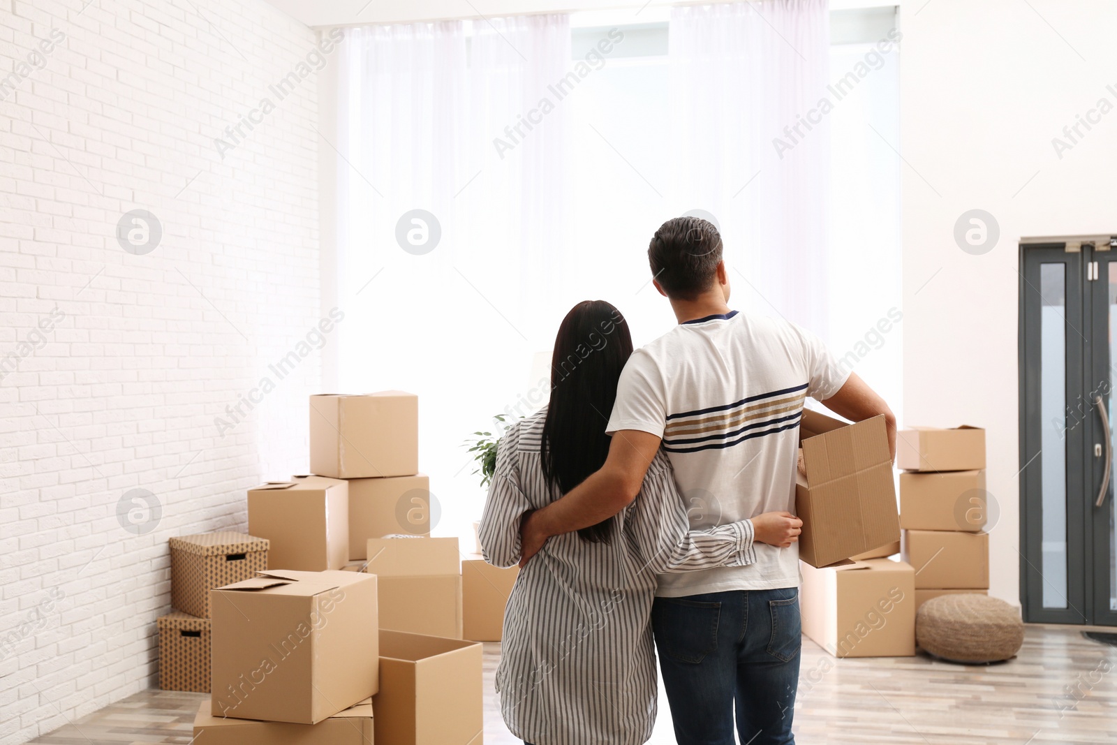 Photo of Couple in room with cardboard boxes on moving day