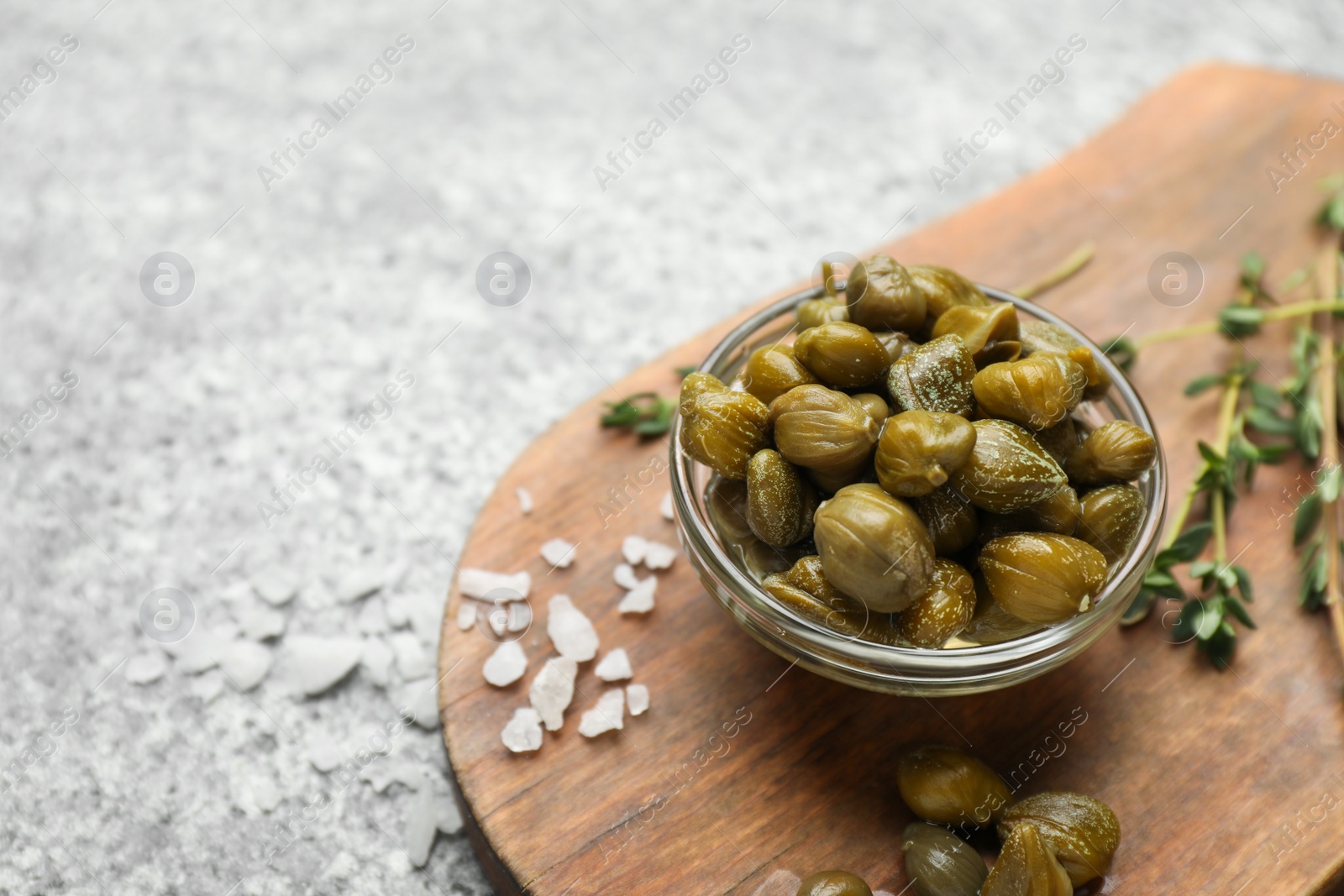 Photo of Tasty capers, salt and thyme on grey table, space for text