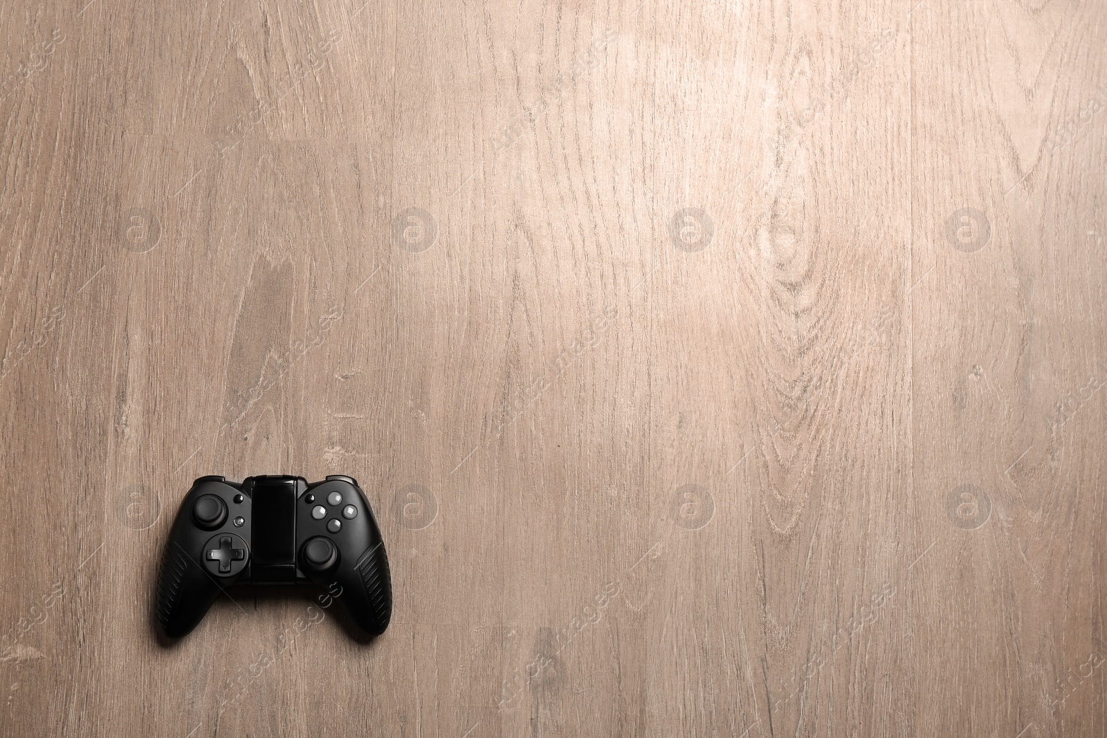 Photo of Video game controller on wooden background, top view with space for text