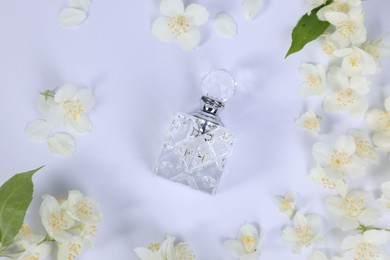 Photo of Aromatic perfume in bottle and beautiful jasmine flowers on white background, flat lay