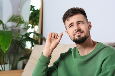 Young man cleaning ear with cotton swab at home. Space for text