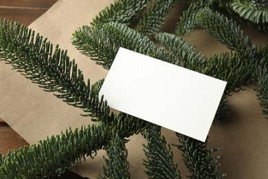 Photo of Blank business card and fir branches on wooden table, closeup. Space for text