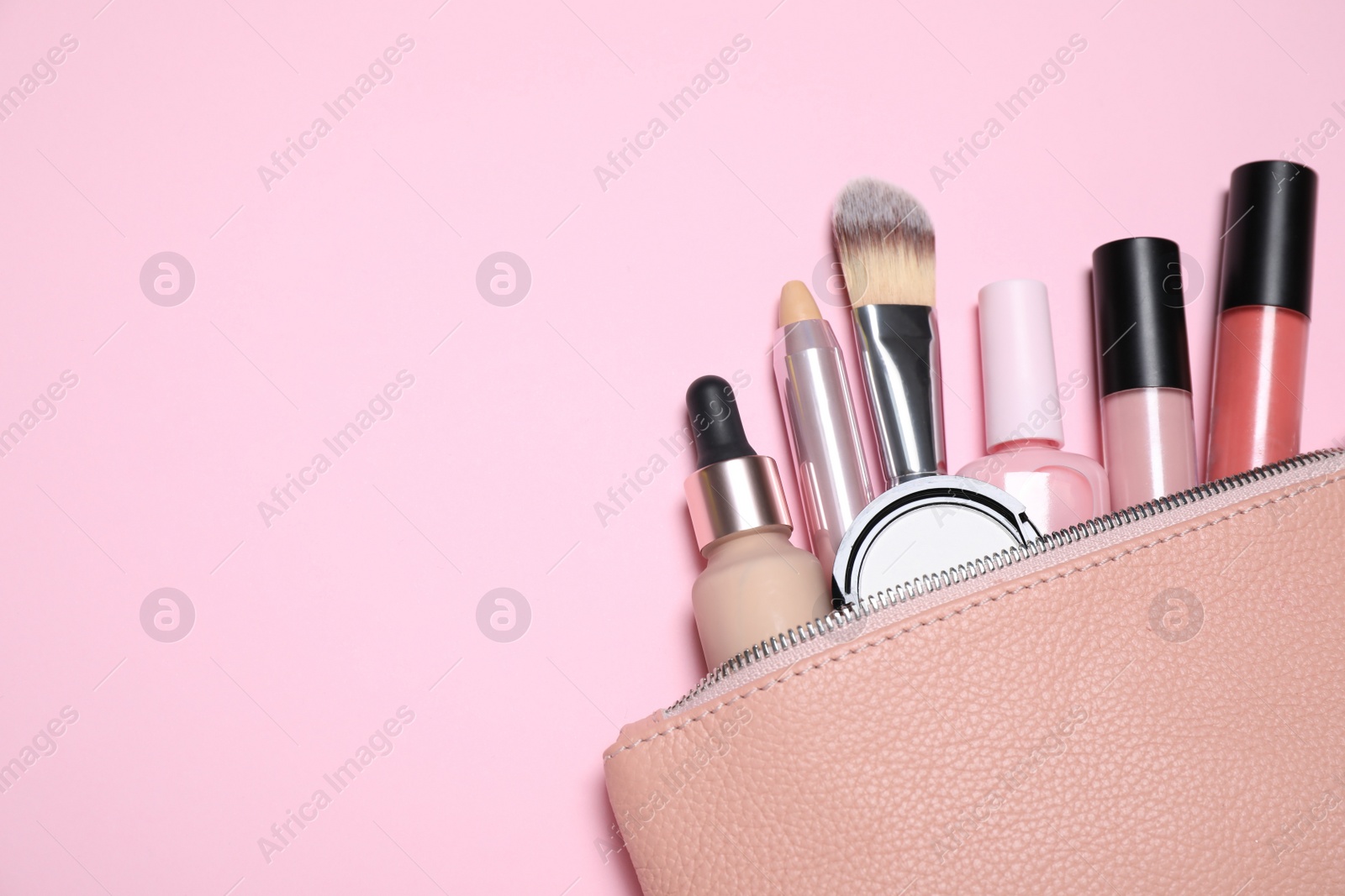 Photo of Cosmetic bag with make up products on light pink background, flat lay. Space for text