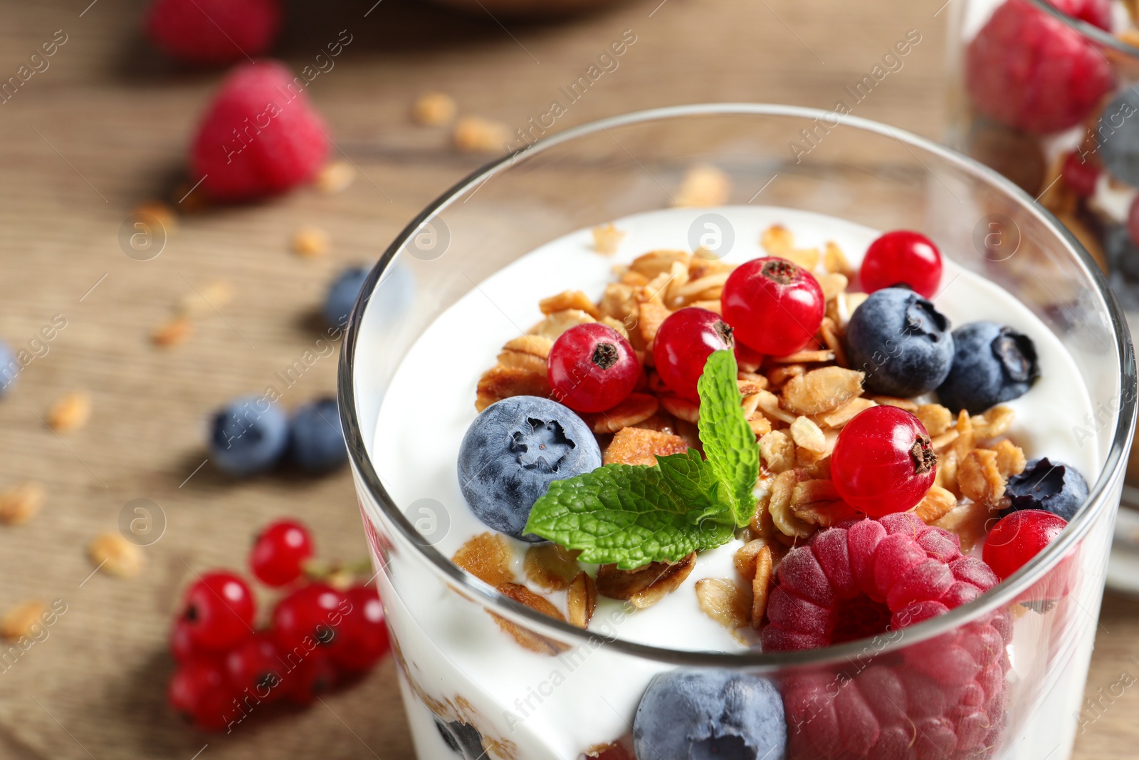 Image of Tasty dessert with yogurt, berries and granola on wooden table, closeup