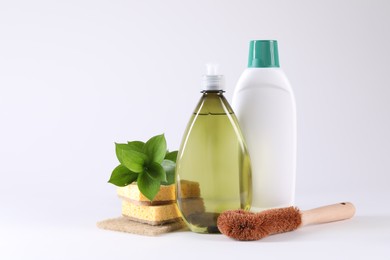 Bottles of cleaning product, brush and sponges on white background