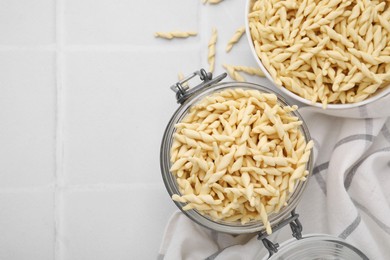Photo of Uncooked trofie pasta on white tiled table, flat lay. Space for text