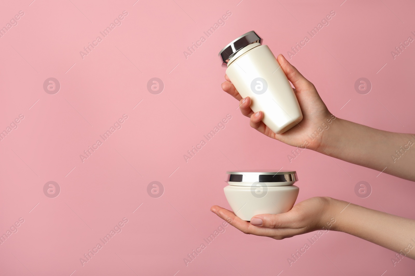 Photo of Woman holding hair care cosmetic products on pink background, closeup. Space for text