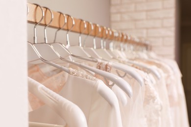 Photo of Different wedding dresses on hangers in boutique, closeup