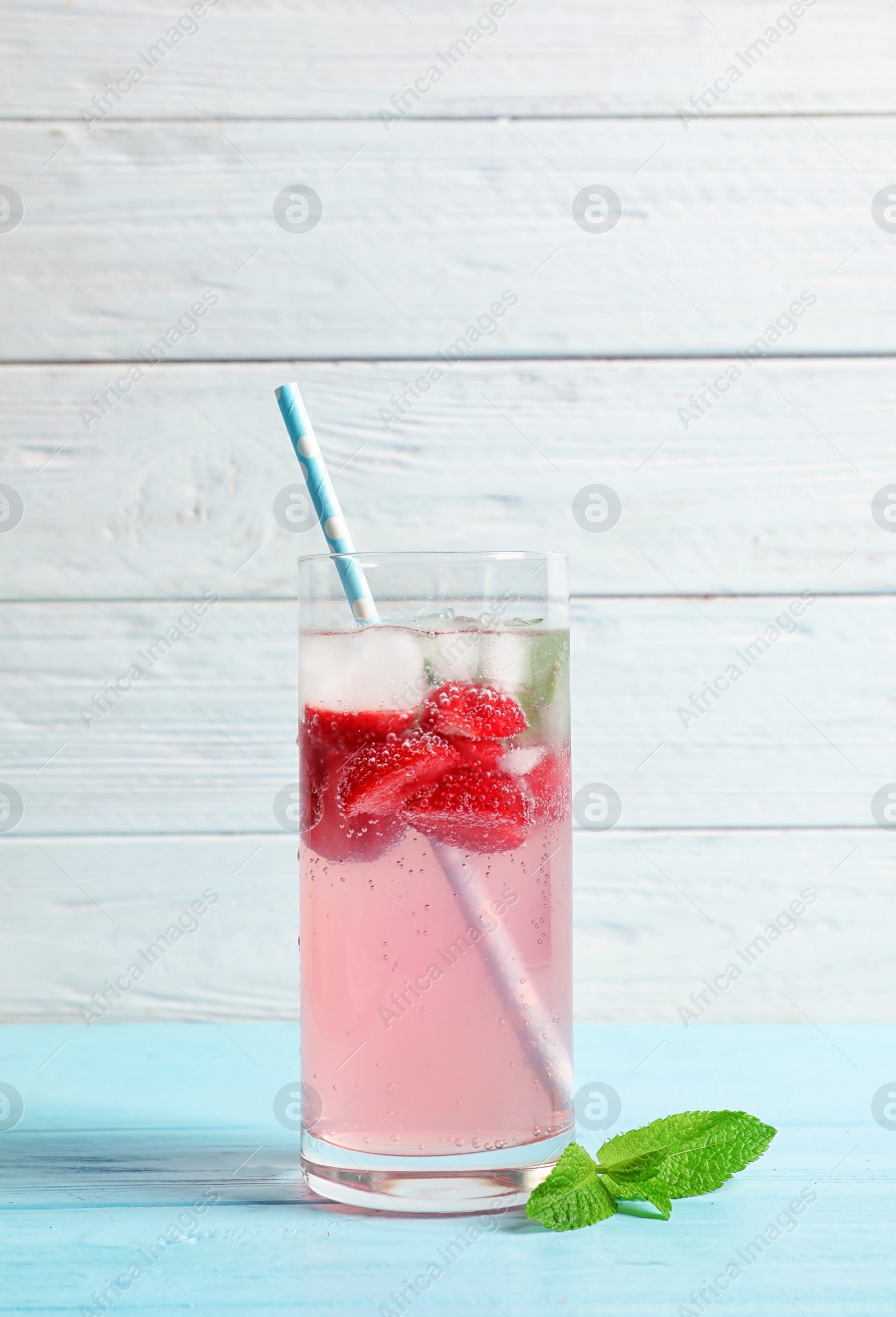 Photo of Natural lemonade with strawberries in glass on wooden table