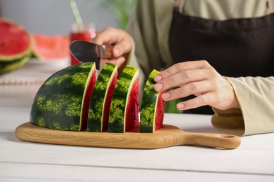 Photo of Woman cutting delicious watermelon at white wooden table indoors, closeup