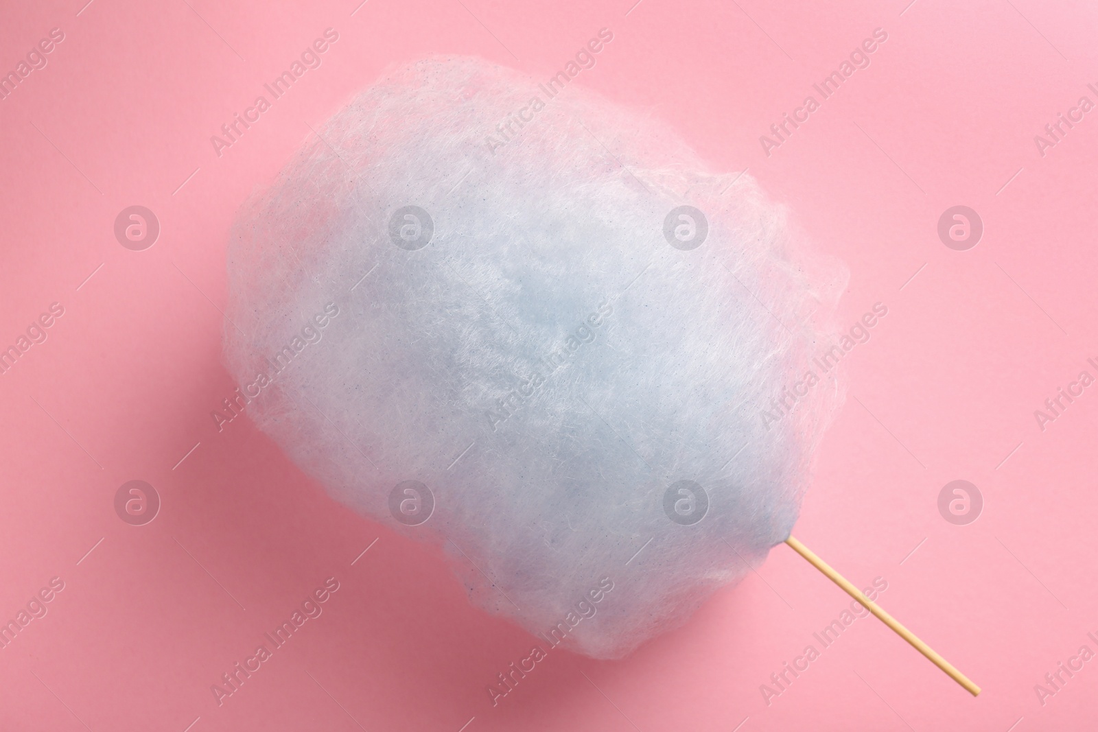 Photo of Sweet light blue cotton candy on pink background, top view