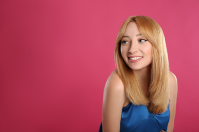 Photo of Beautiful young woman with blonde hair on pink background. Space for text