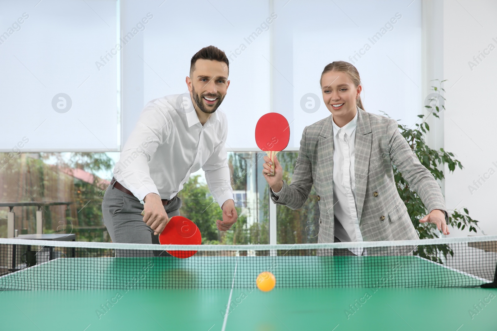 Photo of Business people playing ping pong in office