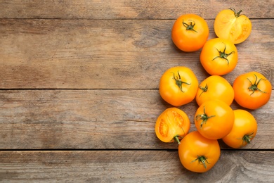 Photo of Ripe yellow tomatoes on wooden table, flat lay. Space for text