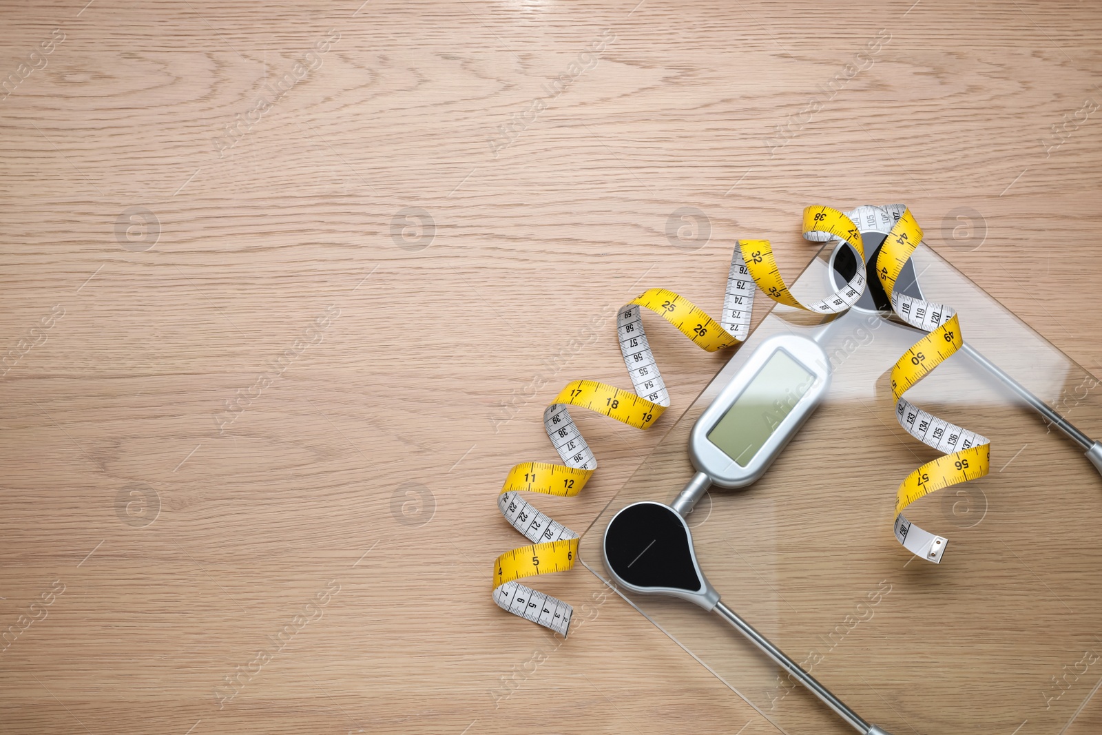 Photo of Electronic scales and measuring tape on wooden background, flat lay. Space for text