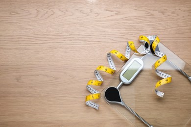 Electronic scales and measuring tape on wooden background, flat lay. Space for text