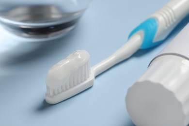 Photo of Plastic toothbrush with paste and tube on light background, closeup